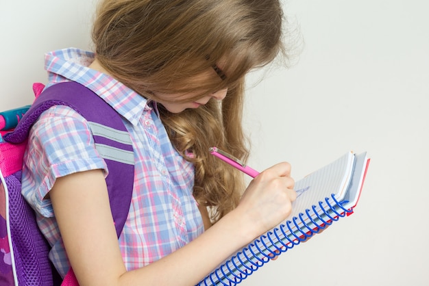 Niña estudiante de escuela primaria escribiendo en su cuaderno.