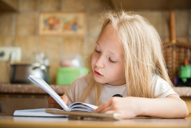 Niña estudiante leyendo un libro en casa