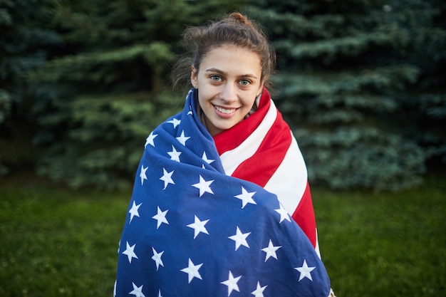 Niña estudiante sonriente envuelta en la gran bandera nacional