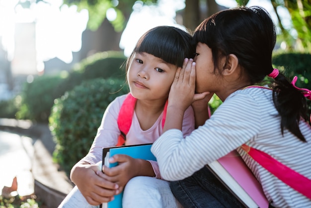 Niña estudiante susurrando a su amiga