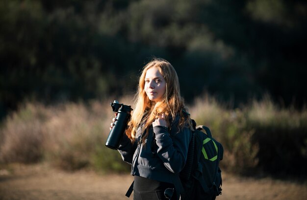 Niña excursionista con mochila subió una colina y mirando el paisaje impresionante y salvaje hermoso