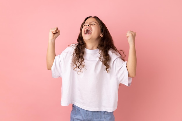 Niña expresando gesto ganador con puños levantados y gritando celebrando la victoria