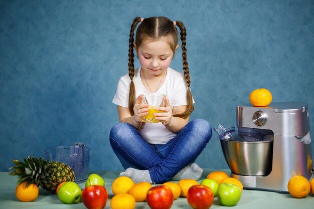 Niña exprimió jugo fresco de frutas de manzanas y naranja. Vitaminas y nutrición saludable para niños.