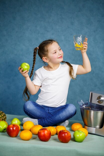 Foto niña exprimió jugo fresco de frutas de manzanas y naranja. vitaminas y nutrición saludable para niños.