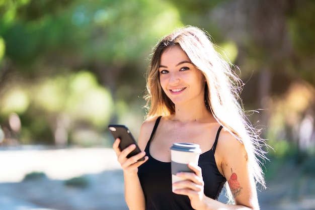 Niña en el exterior con café para llevar mientras envía un mensaje con el móvil