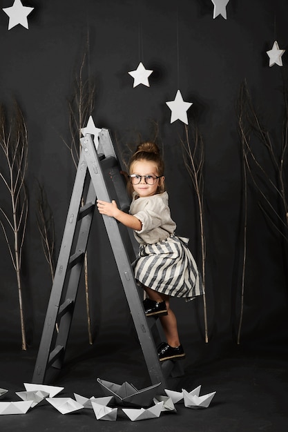 Niña de Fanny con gafas sobre fondo gris con estrella y escalera