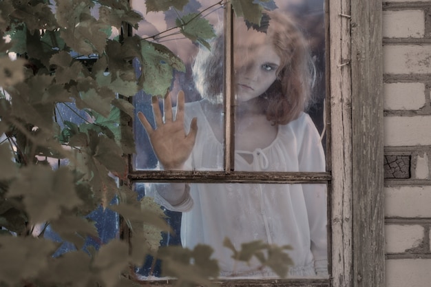 Niña fantasma en la ventana vieja