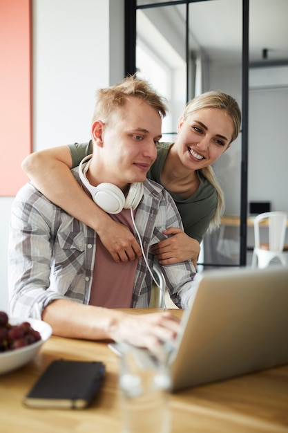 Niña feliz abrazando a su novio frente a la computadora portátil