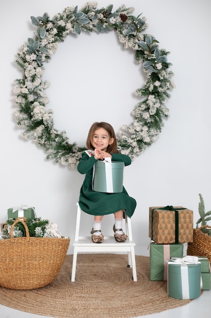 Niña feliz abre los regalos cerca del árbol de Navidad de la guirnalda en casa