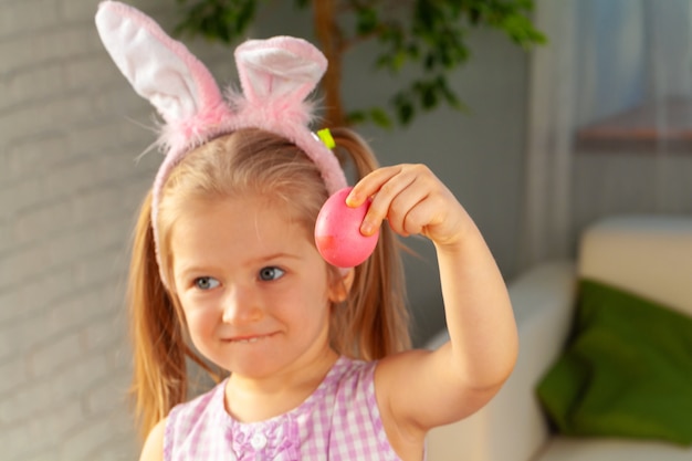 Niña feliz acaba de pintar un huevo para Pascua