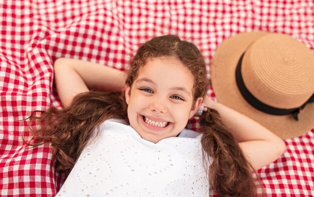 Niña feliz acostada en una manta para picnic