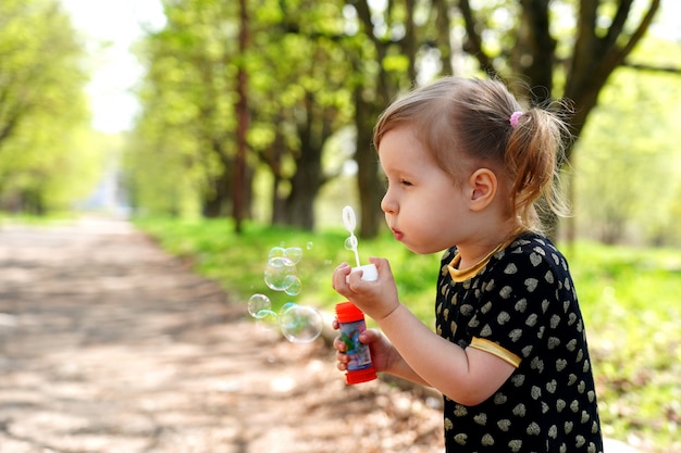 Niña feliz al aire libre en el parque de pompas de jabón