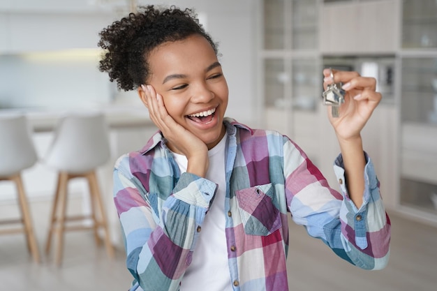 Niña feliz alquila su primera casa Una joven afroamericana llena de alegría tiene la llave