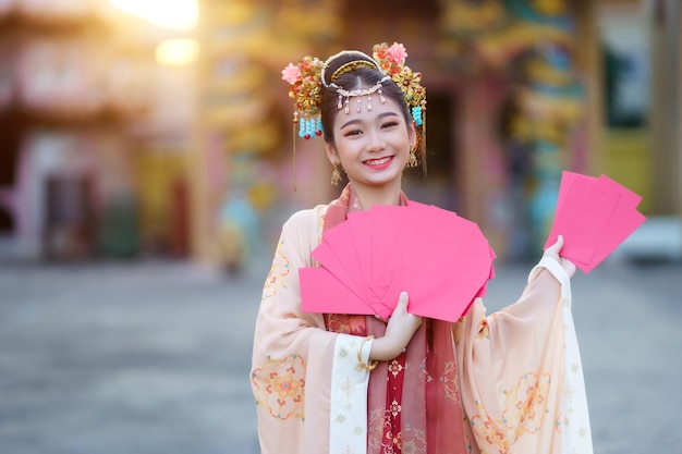 Niña feliz asiática vestida con trajes chinos con decoración de sobres rojos para el festival de año nuevo chino celebra la cultura de China en el santuario chino Lugares públicos en Tailandia