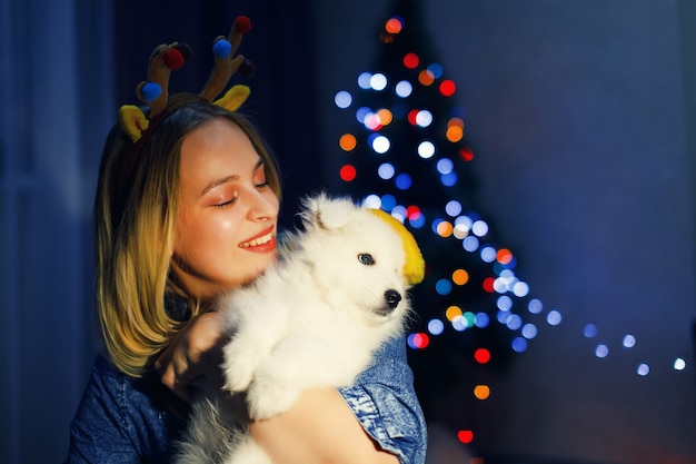 Niña feliz en asta con perro husky samoyedo en adornos navideños