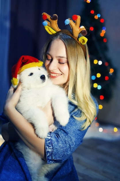 Niña feliz en asta con perro husky samoyedo en adornos navideños