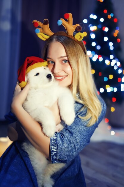 Niña feliz en asta con perro husky samoyedo en adornos navideños