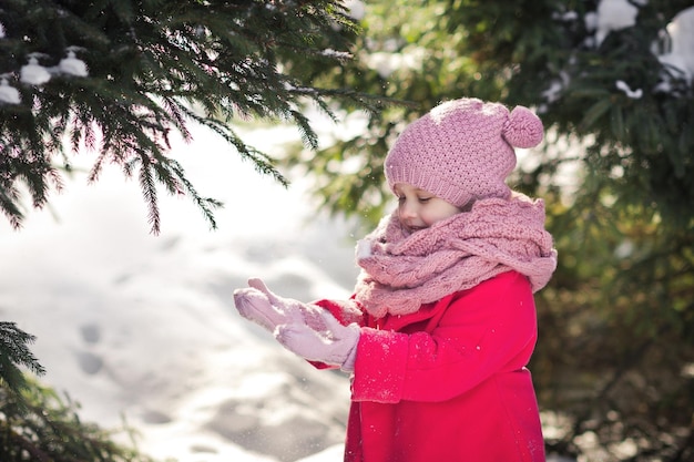 Niña feliz atrapa copos de nieve que caen de los árboles 952