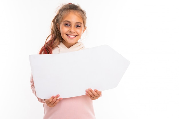 Foto niña feliz con auriculares muestra hacia gran flecha blanca y se regocija