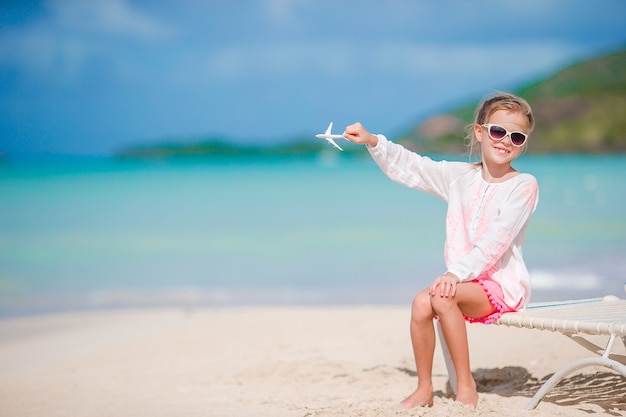 Niña feliz con avión de juguete en las manos en la playa de arena blanca. Niño juega con juguetes en la playa