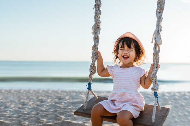 Niña feliz balanceándose en la playa