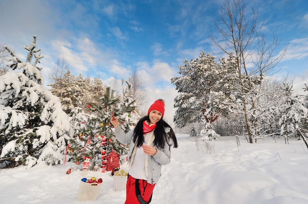 Niña feliz en el bosque de invierno toma un selfie cerca del árbol de Navidad. Una mujer sonríe en un bosque cubierto de nieve el día de Navidad