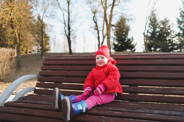 Niña feliz en botas y chaqueta roja niña alegre divertida jugando al aire libre