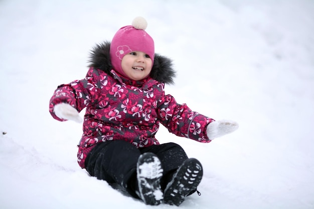 niña feliz cabalgando sobre una colina helada