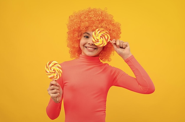 Foto niña feliz con cabello naranja en poloneck rosa diviértete sosteniendo paletas de infancia