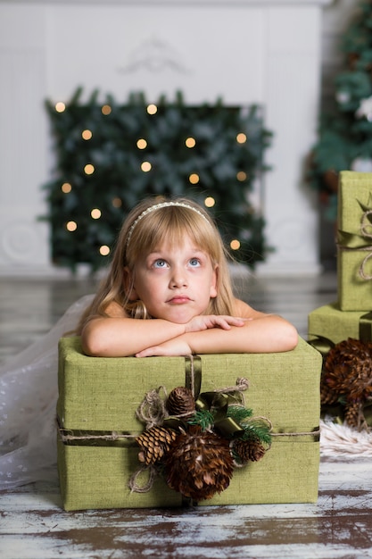 Niña feliz con una caja grande con un regalo sobre su cabeza.