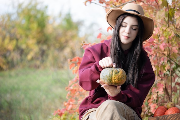 Niña feliz con calabaza en el jardín de otoño