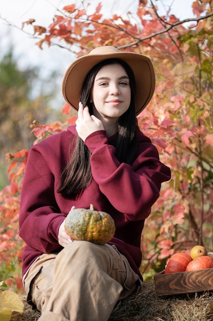 Niña feliz con calabaza en el jardín de otoño