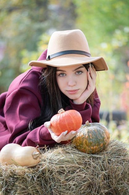 Niña feliz con calabaza en el jardín de otoño