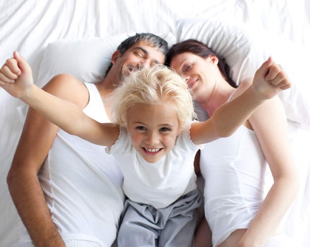 Niña feliz en la cama con sus padres