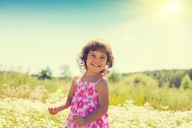 Niña feliz camina en el campo de flores