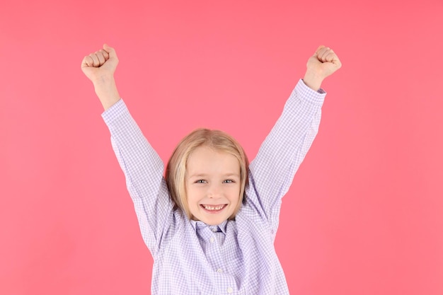 Niña feliz en camisa sobre fondo rosa