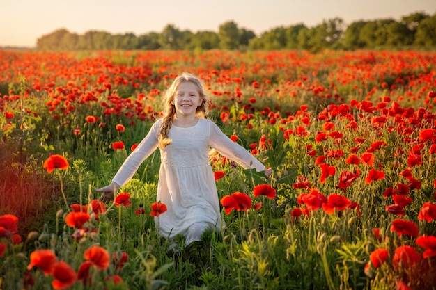 Niña feliz en campo de amapolas