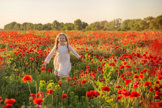 Niña feliz en campo de amapolas