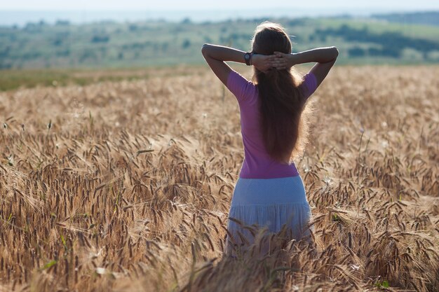 Niña feliz en el campo de trigo dorado