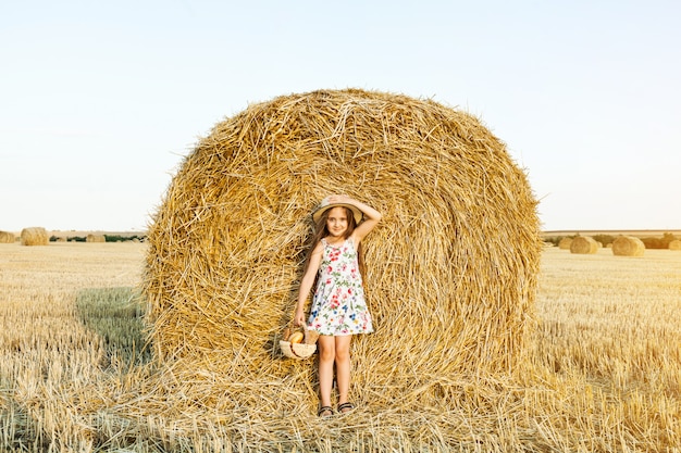 Niña feliz en el campo de trigo con pan