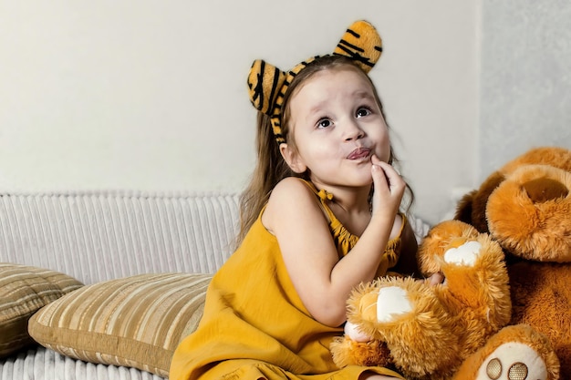 niña feliz en casa en el sofá con juguetes