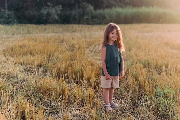 Niña feliz celebrando extendiendo sus manos en un campo amarillo Foto de alta calidad