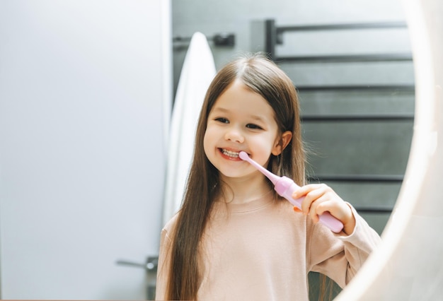 Niña feliz cepillándose los dientes frente a un espejo de baño Higiene matutina