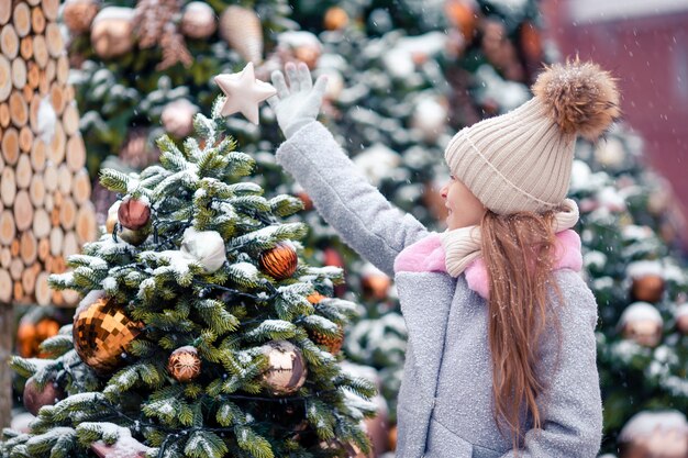 Niña feliz cerca de rama de abeto en la nieve por año nuevo.