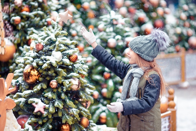 Niña feliz cerca de rama de abeto en la nieve por año nuevo.