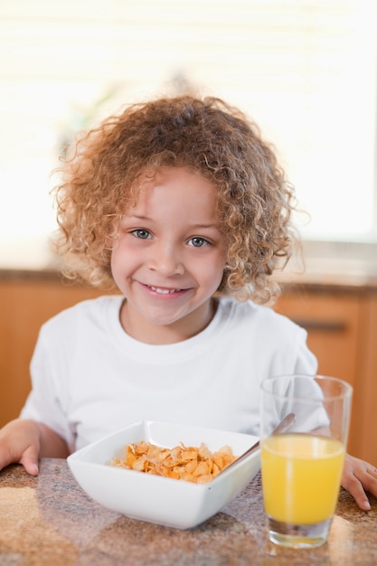 Niña feliz con cereales y jugo de naranja para el desayuno