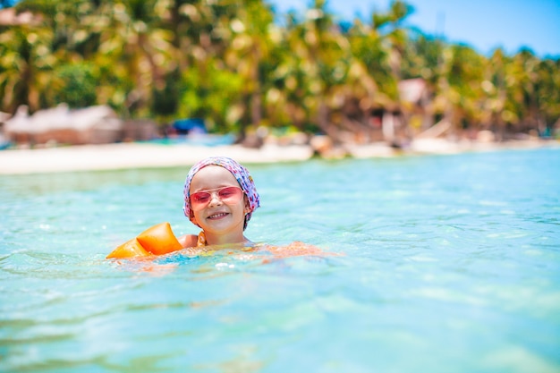 Niña feliz chapoteando en agua turquesa clara