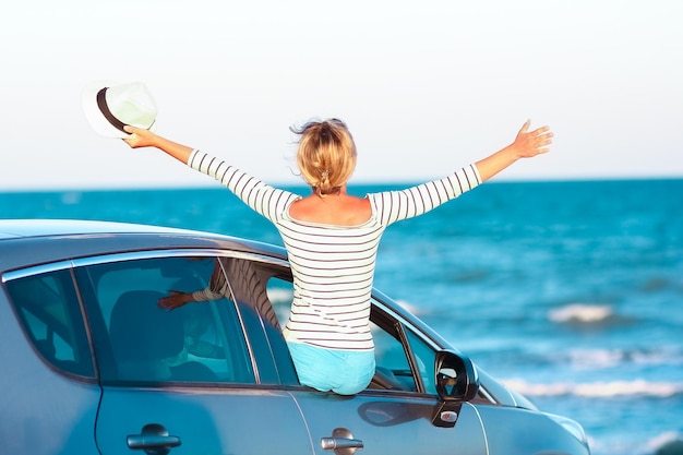 Una niña feliz en el coche junto al mar en la naturaleza en viajes de vacaciones