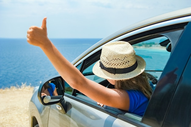 Una niña feliz del coche en el mar.