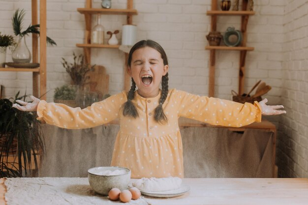 una niña feliz cocina un pastel en la cocina con un vestido de algodón. foto de alta calidad